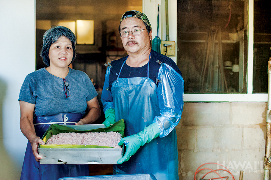  /><figcaption><em>Kapaa Poi Factory owners Susan and Rankin Pang, with a tray of fresh-made kulolo. Photo: Mike Coots.</em></figcaption></figure>
</div>
<p>Generations ago, kulolo was only made with the freshest of its basic ingredients—just-harvested kalo, fresh-cracked coconut meat and milk, and raw sugar. The mixture was wrapped in ti leaves and baked in an <em>imu</em> (underground oven) for hours. Today’s commercially sold kulolo is often made with processed sugar and canned coconut milk—the fresh stuff is too difficult to obtain in sufficient quantity—and baked in standard ovens for less than half the time an imu takes to finish it. Then there’s the kalo, likely the reason you’ll find more kulolo, more kulolo makers and more varieties of kulolo on Kauai.</p>
<p>According to the U.S. Department of Agriculture, Kauai is the state’s largest producer of kalo, accounting for nearly 80 percent of the state’s annual harvest. Kulolo aficionados say that good kalo makes all the difference in the dessert’s taste. A good many of these fans also believe that the best kalo in the state is grown on the island with the most acreage devoted to the crop.</p>
<p>“Kauai has the best taro, absolutely, no question,” says Rankin Pang, who, along with his wife, Susan, operates the Kapaa Poi Factory in the East Kauai town of Kapaa. “You cannot make good kulolo without good taro.”</p>
<p>The Pangs are the third generation of their family to run the factory, processing more than a thousand pounds of kalo a week to make their signature kulolo. Grown on a handful of local farms, the kalo is combined with canned coconut milk and sugar to make the dessert. The factory, a simple building built in 1947, with a galvanized iron roof—a veteran of two hurricanes—is located in the Kapaa-area highlands, seven winding miles inland from island-circling Kuhio Highway. The factory produced fresh <em>poi </em>until 1998, when its milling machines broke down. Today, kulolo, which Kapaa Poi Factory has been making and selling for more than 50 years, is its only product.</p>
<p>Susan and Rankin—sometimes with their teenage daughter, her friends and Susan’s 81-year-old mother—prepare, mix and bake all of Kapaa Poi Factory’s kulolo. The process begins with the cleaning and skinning of the <em>lehua</em> (red) variety of kalo—the only type the Pangs use. The kalo is next chopped, grated and mixed with sugar and coconut milk, transferred to a baking pan and steamed for several hours. The whole process, from start to finish, spans a couple of days.</p>
<p>Kapaa Poi Factory’s kulolo recipe was handed down from Susan Pang’s uncle, Kenneth Lai. Kenneth and his brother, Koon Chow Lai, began running the business in 1956.</p>
<p>“He talked to people and experimented,” Susan says of her uncle Kenneth. “We added kulolo [to the factory’s production] because we had so much kalo back then.”</p>
<p>Over the years since, the Pangs have changed the original recipe, which called for fresh coconut milk and local sugar. Only a handful of people—all of them family members—are privy to the recipe.</p>
<p>At its busiest in the early 2000s, the factory cranked out more than twice the kulolo it currently does. Business is steady, but the Pangs have ramped down production to a manageable amount, allowing most of the work—from cleaning to packaging—to be completed themselves. The bulk of Kapaa Poi Factory’s kulolo is sold at Kauai markets in brick-size packages. The factory ships kulolo to Oahu weekly and has, on occasion, shipped trays overnight to California, Nevada, Utah and Texas. Customers have asked the Pangs to create variations of their kulolo—adding bananas or giving it different hues, for example. The original-recipe kulolo, however, is still the only one you’ll find for sale.</p>
<div style=