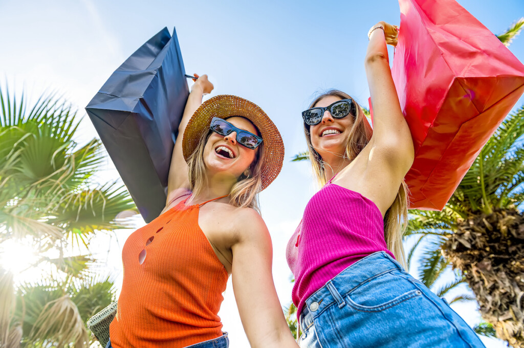 Two Beautiful Young Women Enjoying Shopping In The City Street Happy And Smiling Sisters After Shopping Raise Their Shopping Bags To The Sky Sale, Consumerism And People Concept