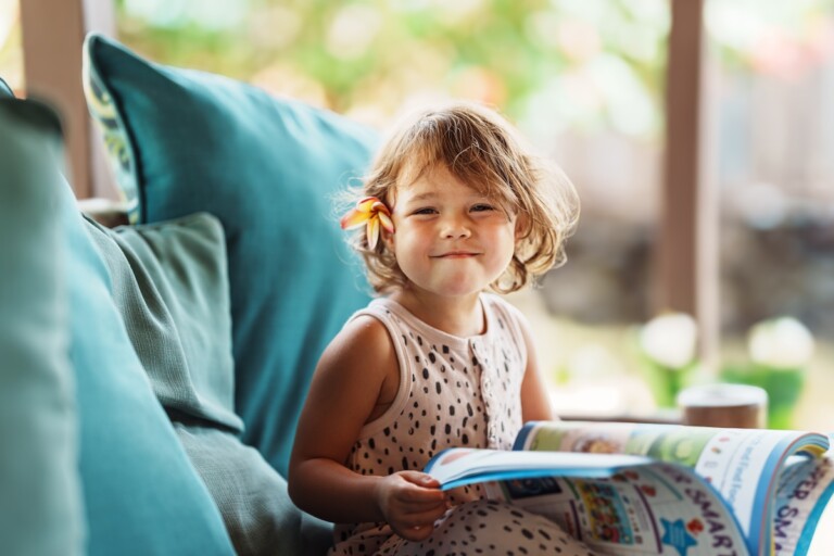 Eurasian Preschool Age Girl Reading A Book At Home On The Patio